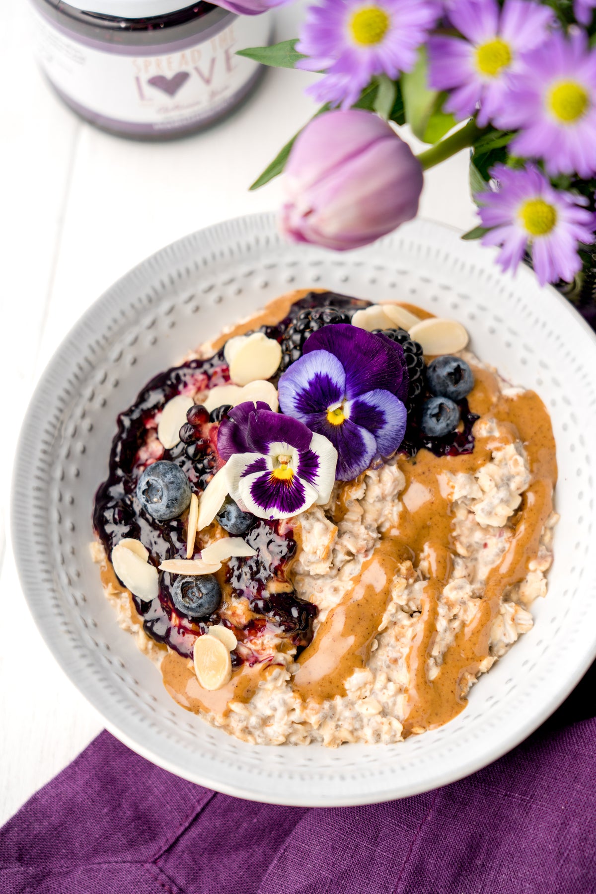 Bowl of Almond Butter Jam Overnight Oats topped with berries, almond butter, and jam
