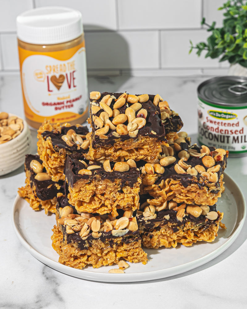 Plate of no bake chocolate cornflake bars wuth Spread The Love Peanut Butter and Let's Do Organic Organic Sweetened Condensed Coconut Milk in the background
