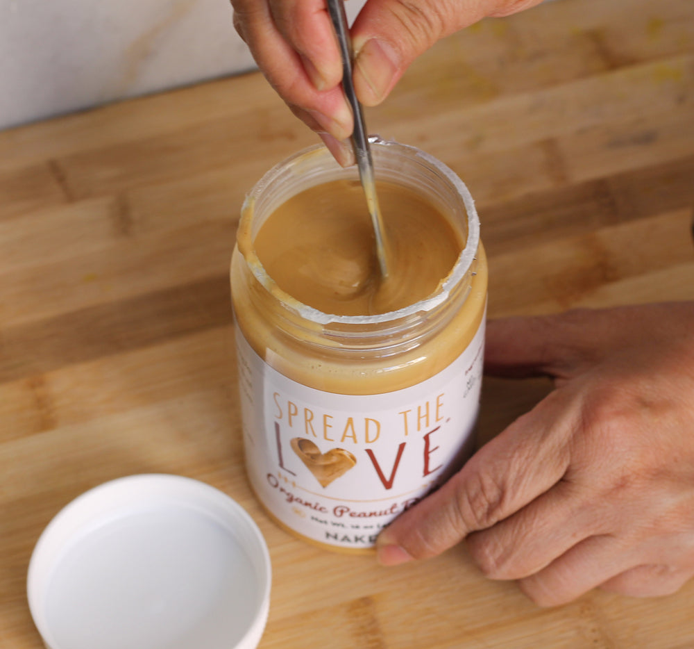 Photo of someone stirring a jar of Spread The Love Peanut Butter