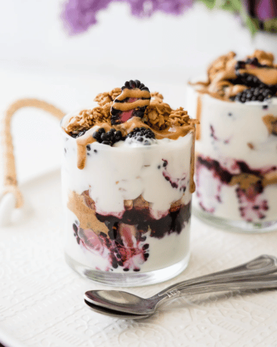 Two glass cups of Marionberry Jam parfait topped with Almond Butter and granola