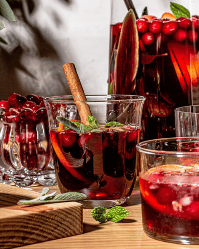Pitcher and cups full of Marionberry Jam Sangria with cranberries