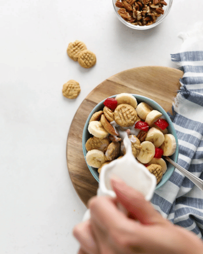 Pouring milk into a bowl of peanut butter cookie cereal