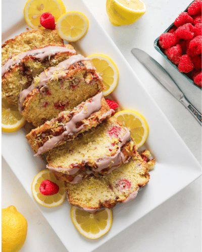 Plate of sliced Raspberry Lemon Quick Bread with lemons and raspberry