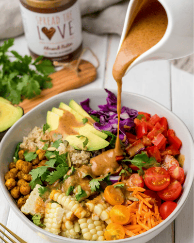 Rainbow Salad Bowl with Almod Butter Dressing being drizzled