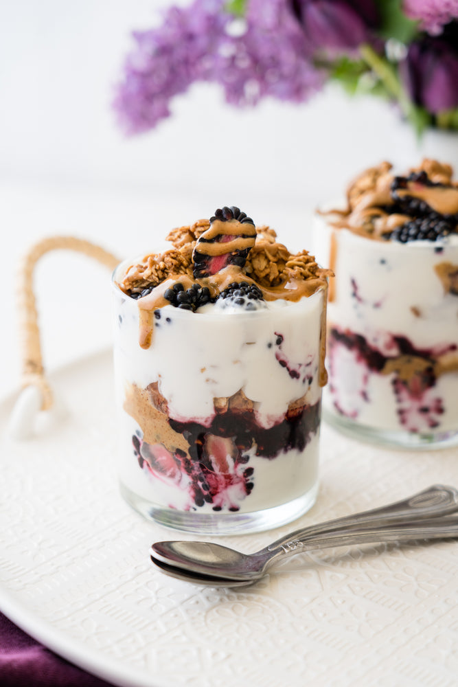 Two glass cups of Marionberry Jam parfait topped with Almond Butter and granola