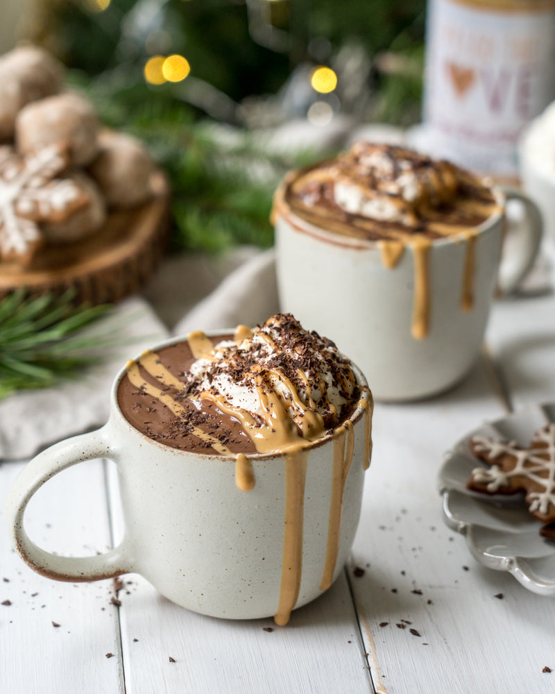 Two mugs of peanut butter hot chocolate with peanut butter drizzle