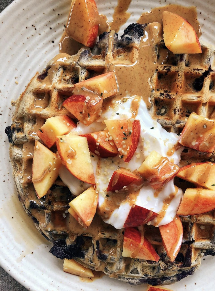 Plate of Blueberry Cinnamon Oat Waffles topped with Spread The Love Almond Butter and apples