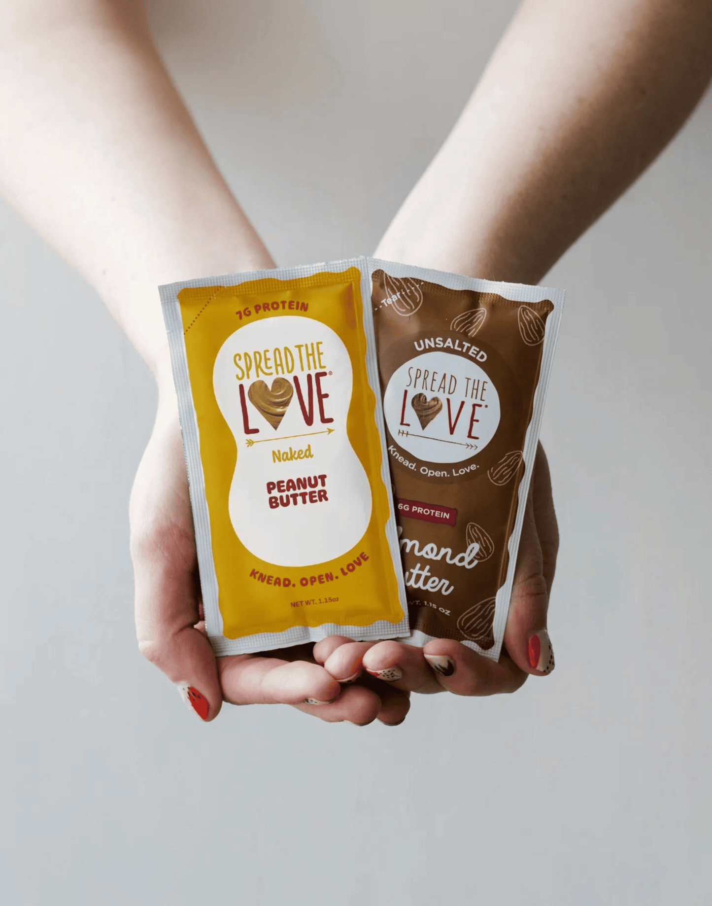 Someone holding the Spread The Love Peanut Butter and Almond Butter Packets.