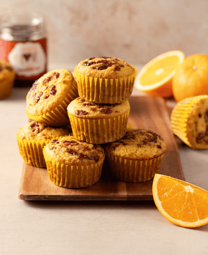 Plate stacked with Raspberry Orange Muffins with orange slices around