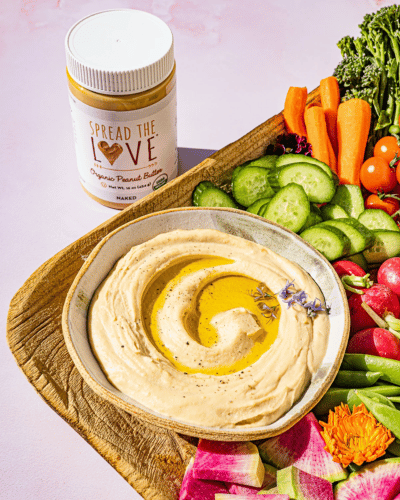 Veggie board with Savory Peanut Dip and a jar of Spread The Love Peanut Butter