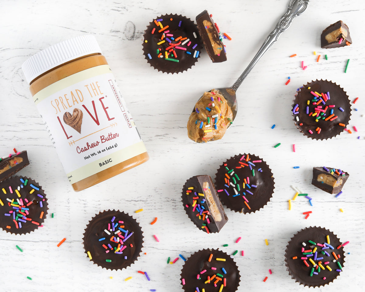 Cashew Butter Jar surrounded by Birthday Cake Cashew Butter Cups, sprinkles, and spoonful of Cashew Butter