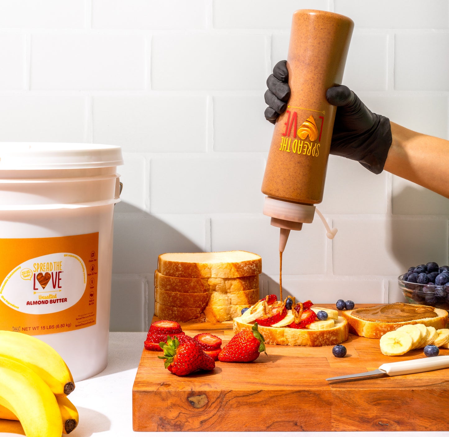 Spread The Love Almond Butter drizzle on berry toast with squeeze bottle