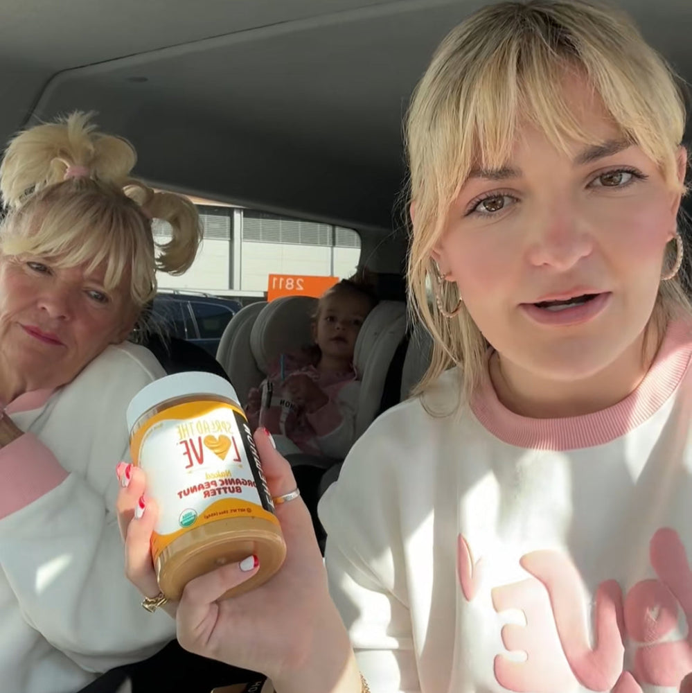 Two women in a car, one holding a jar of peanut butter.