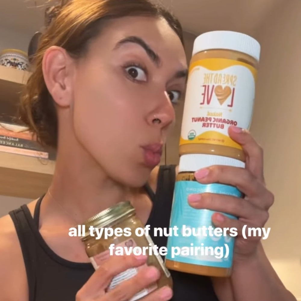 Woman holding two jars of nut butter with a kitchen background