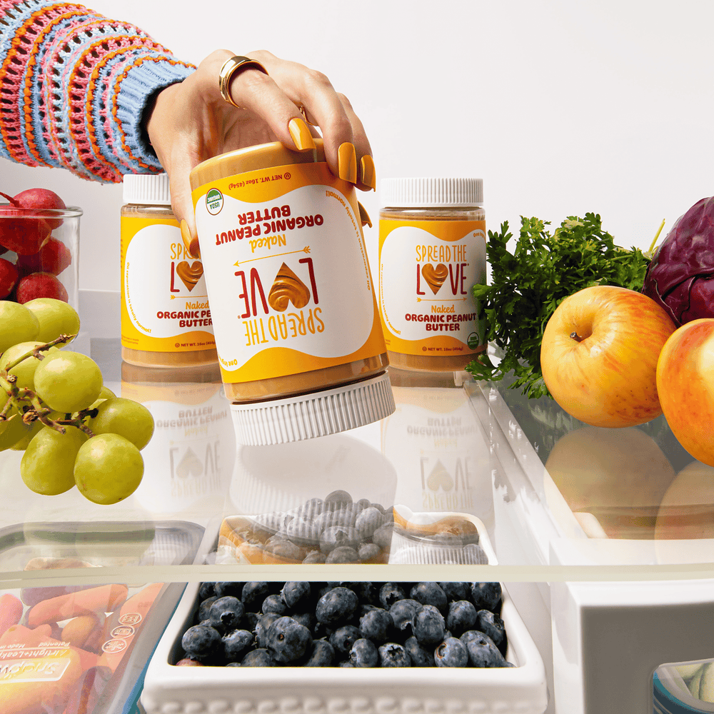 
                  
                    Load image into Gallery viewer, Hand holding a jar of Spread The Love Organic Peanut Butter upside down
                  
                