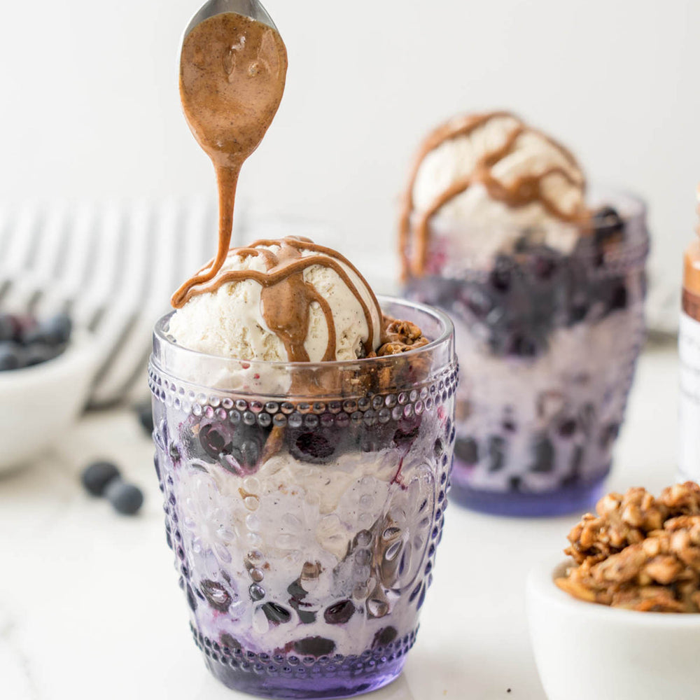 
                  
                    Load image into Gallery viewer, Spread The Love Unsalted Almond Butter being drizzled on an ice cream parfait with blueberries and granola.
                  
                